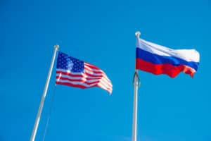 Russian Federation and USA United States of America flags on a blue sky background. idea of the sanctions war combat negotiation and confrontation. Source; shutterstock.com