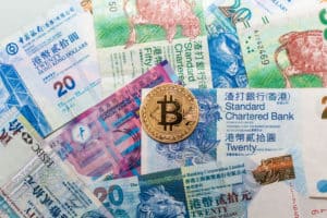 Gold Bitcoin with actual Hong Kong Dollar currency banknote indicating dangerous of cryptocurrency. Source: shutterstock.com