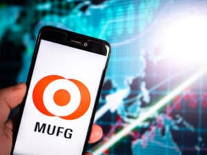Murcia, Spain; Oct 18, 2018 Mitsubishi UFJ Financial Group logo in phone with earnings graphic on background. Hand holding