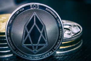 The Coin cryptocurrency EOS on the background of a stack of coins.