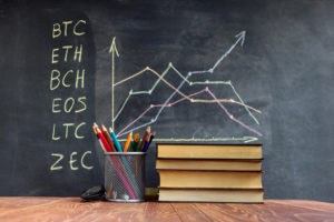 A table with books on the background of graphs on a chalkboard. Learning crypto currency in school. Concept, a new educational subject for children. - Image
