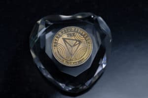 Tron TRX cryptocurrency physical coin placed on the crystal heart in the dark background - Image