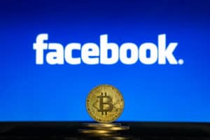 Bitcoin on a stack of coins with Facebook logo on a laptop screen. Cryptocurrency and blockchain adoption getting mainstream. Slovenia - 02 24 2019 - Image