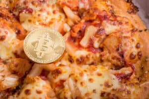 Pizza and golden physical bitcoin, concept of buying pizza with bitcoin, bitcoin pizza day anniversary - Image
